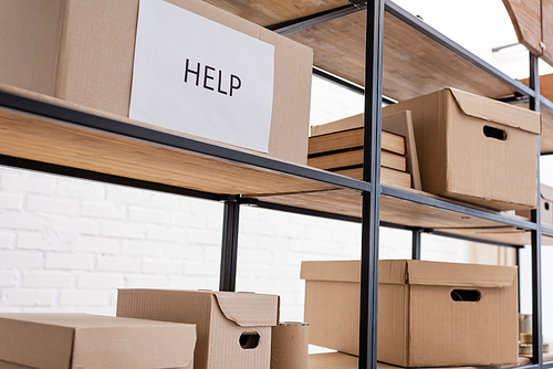 carton box with help lettering on rack in charity warehouse