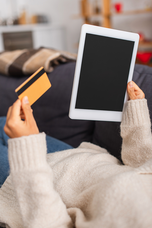 Cropped view of african american woman holding digital tablet with blank screen and credit card on couch