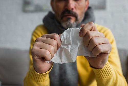 selective focus of crumpled paper napkin in hands of cropped diseased man on blurred background