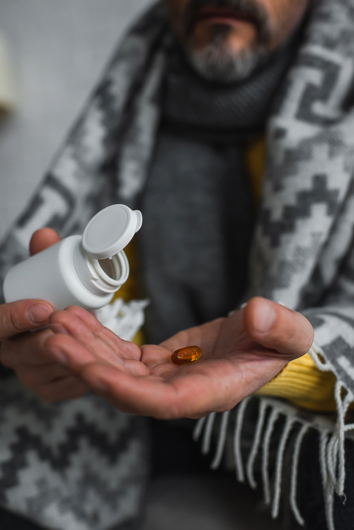 cropped view of diseased man holding container and pill on blurred background