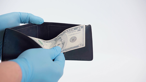cropped view of person in latex gloves holding dollar banknote and wallet on white