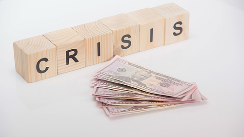 dollar banknotes near wooden cubes with crisis lettering on white background