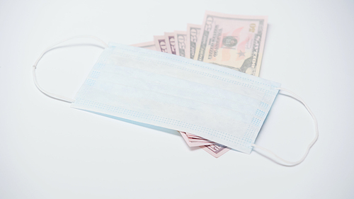 protective medical mask on dollar banknotes on white background