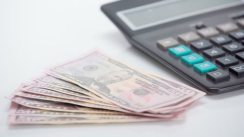 dollar banknotes near blurred calculator on white background