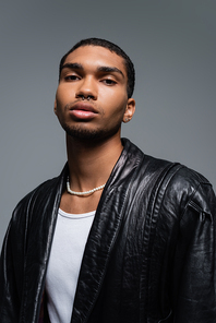 portrait of young african american man in leather jacket posing isolated on grey