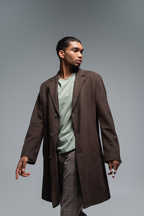 young african american man in woolen coat standing isolated on grey