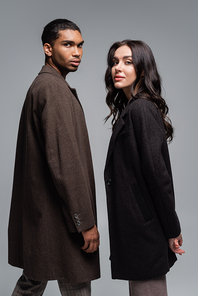 young african american man in coat near stylish woman in black blazer isolated on grey