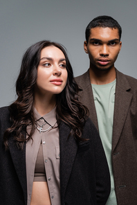 young african american man and brunette woman in stylish blazer isolated on grey