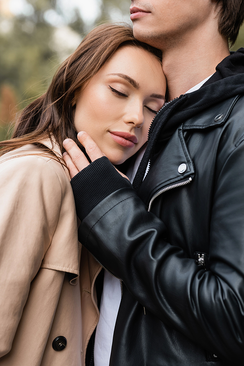 pretty young woman with closed eyes leaning on chest of boyfriend