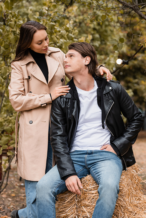 brunette woman in trench coat hugging stylish boyfriend in autumnal park