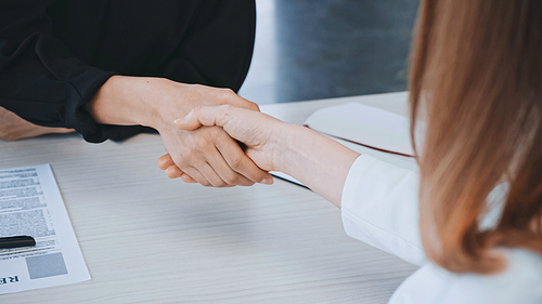 cropped view of employer and job seeker shaking hands near resume in office