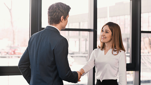 businessman shaking hands with cheerful woman after job interview