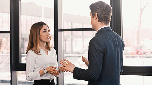 businessman and smiling woman gesturing during conversation on job interview