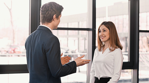 businessman pointing with hands at happy woman during job interview