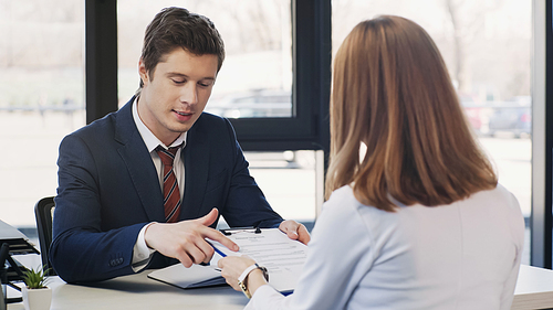 man pointing at resume during job interview with businesswoman in office