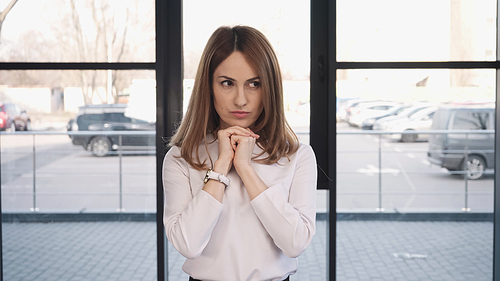 worried woman holding hands near face and looking away while waiting for job interview