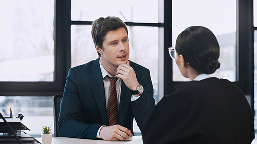 attentive businessman listening to brunette woman during job interview