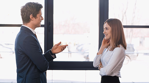 side view of employer pointing with hand while talking to positive woman on job interview