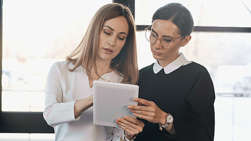 businesswoman showing digital tablet to colleague in office