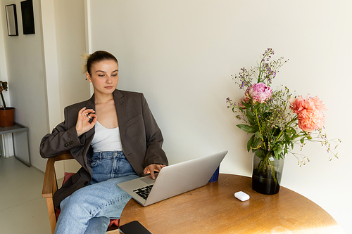Woman in jacket showing ok gesture while using laptop at home
