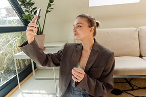 Smiling woman taking selfie on smartphone in living room
