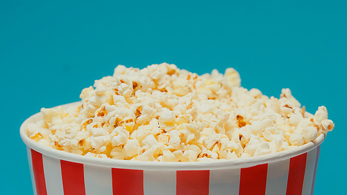 delicious popcorn in big paper bucket isolated on blue
