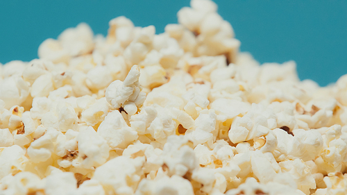 close up view of delicious and salty popcorn isolated on blue
