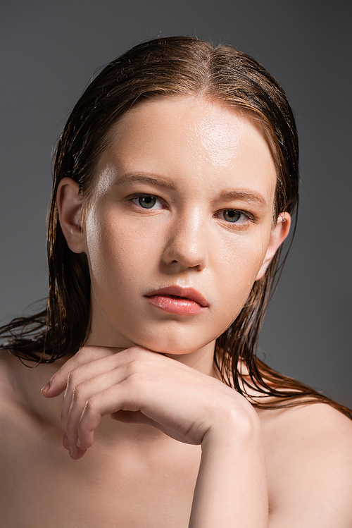 Young woman with wet skin and naked shoulders isolated on grey