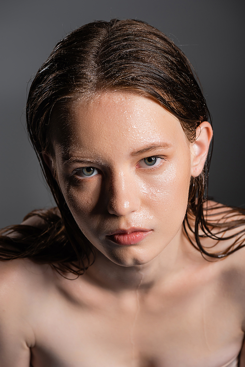 High angle view of model with wet face looking at camera isolated on grey