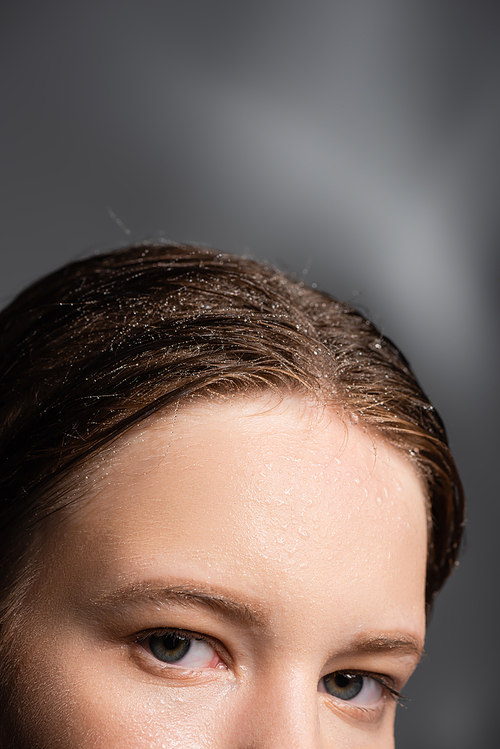 Cropped view of woman with water drops on hair looking at camera on grey background