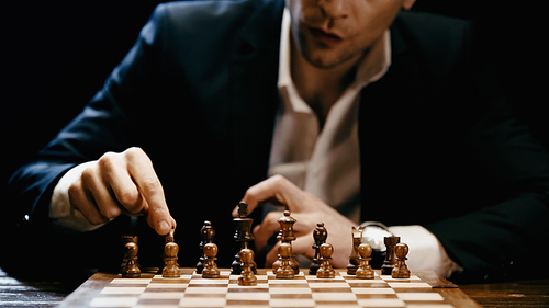 Cropped view of businessman playing chess isolated on black