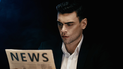 Businessman in suit reading blurred newspaper isolated on black