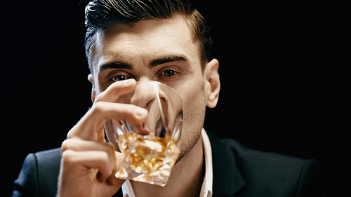 Businessman in formal wear holding glass and drinking whiskey isolated on black