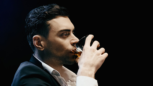 Businessman in formal wear drinking whiskey isolated on black