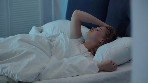 Young woman suffering from insomnia on bed at night