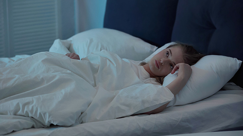 Woman looking away while suffering from insomnia in bedroom at night