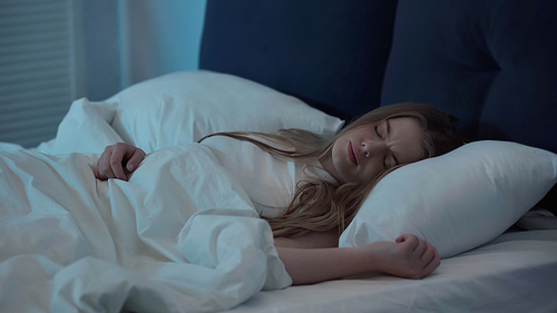 Displeased woman with closed eyes lying on bed at home