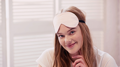 Positive woman in sleep mask looking at camera at home