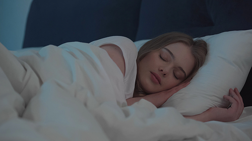 Blonde woman sleeping on bed at home