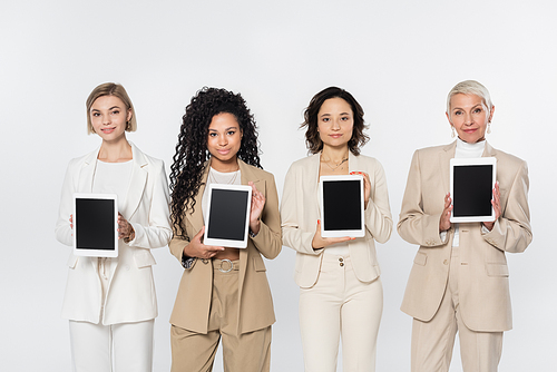 Multiethnic businesswomen holding digital tablets with blank screen isolated on grey