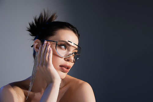 Pretty brunette woman in sunglasses looking away on grey background