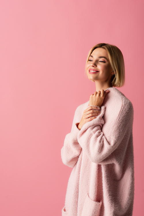 happy young woman in soft cardigan isolated on pink