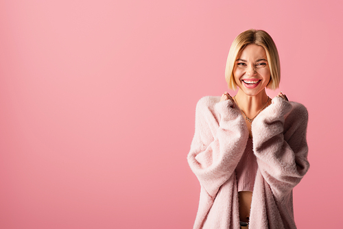 cheerful young woman in soft cardigan isolated on pink