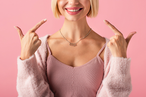 cropped view of happy young woman pointing with fingers at white teeth isolated on pink