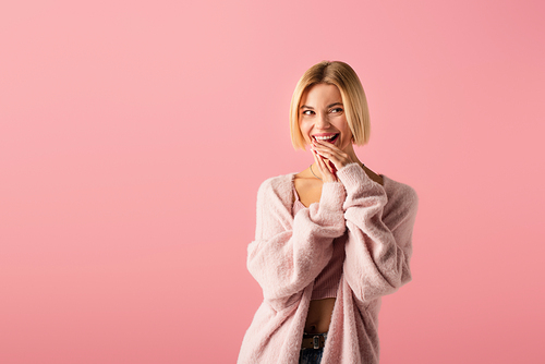 happy young woman in cardigan looking away isolated on pink