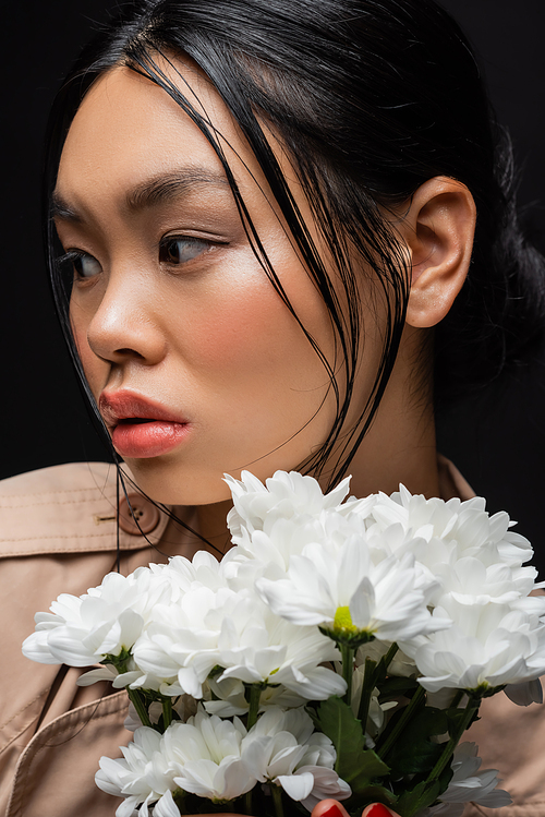 Portrait of young asian woman holding white chrysanthemums isolated on black