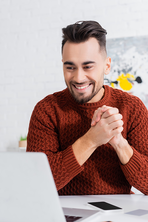 cheerful bookmaker with clenched hands looking at laptop