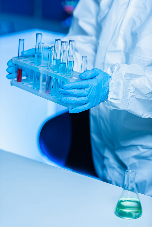 cropped view of bioengineer in latex gloves holding test tubes in laboratory