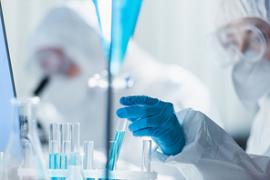 blurred bioengineer in latex glove working with test tubes in laboratory