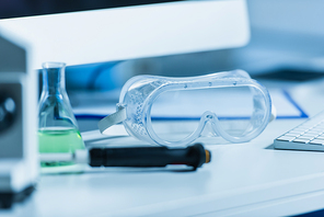selective focus of goggles on desk in bio laboratory on blurred foreground
